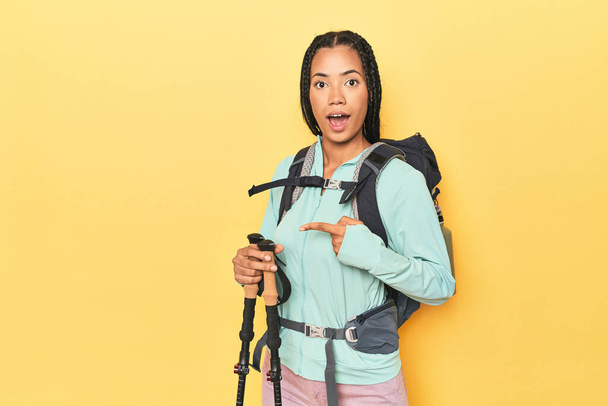 Indonesian woman with hiking gear on yellow pointing to the side - Photo, Image