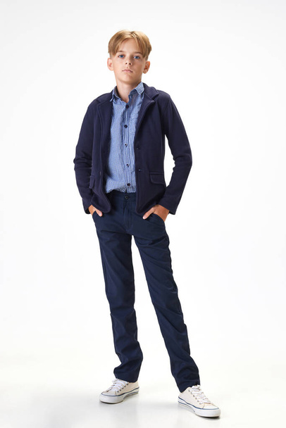 Full-length portrait of boy, child wearing smart casual clothes for school, standing against white studio background. Concept of childhood, school, education, fashion, style. Copy space for ad - Φωτογραφία, εικόνα