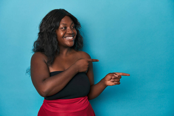 Jovem afro-americana curvilínea mulher animado apontando com os dedos indicador de distância. - Foto, Imagem