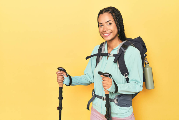 Indonesischer Wanderer mit Rucksack und Stöcken auf gelb - Foto, Bild