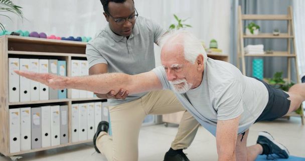 Fizjoterapia, rozciąganie ciała i starszy mężczyzna do rehabilitacji, rehabilitacji i czarny mężczyzna wsparcia klienta. Emerytalna fizjoterapia, mobilność lub afrykański fizjoterapeuta pomagają pacjentom w podeszłym wieku na podłodze. - Zdjęcie, obraz