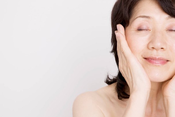 Portrait of mature asian woman with eyes closed with  her hands on face   - Foto, immagini