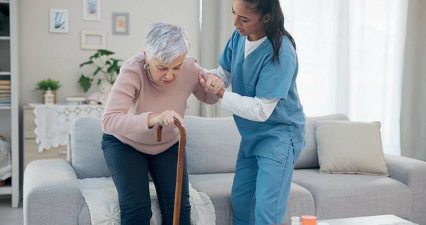 Gondozási támogatás, fogyatékos és idős nő sétapálcával segítségért, magas szintű wellness ellátásért vagy időskori mozgáskorlátozásért. Nyugdíjas, idősek otthonában önkéntes vagy nővér segít a betegnek felkelni. - Fotó, kép