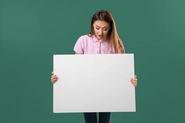 Beautiful woman with big blank poster on green background - Photo, Image