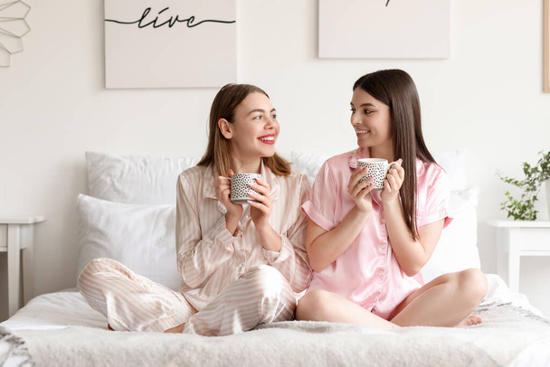 Female friends drinking coffee in bedroom - Photo, Image