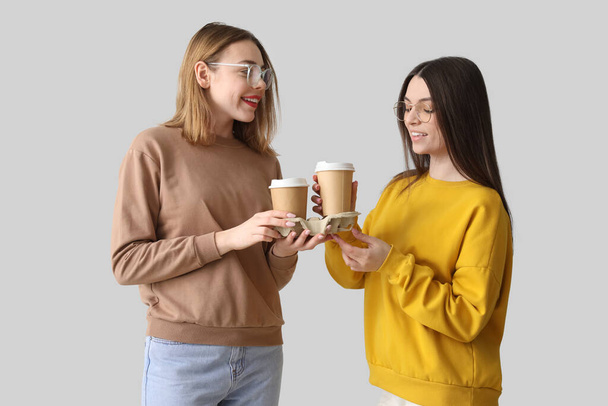 Amigas con tazas de café sobre fondo claro - Foto, imagen