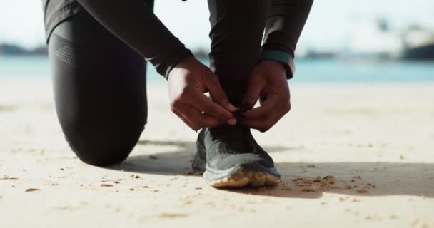 Χέρια, παπούτσια και γραβάτα με έναν άνδρα στην παραλία closeup ενώ ετοιμάζεται για fitness, εκπαίδευση ή τρέξιμο. Άσκηση, υγεία και έναρξη προπόνησης με αθλητή στην άμμο για ευεξία. - Πλάνα, βίντεο