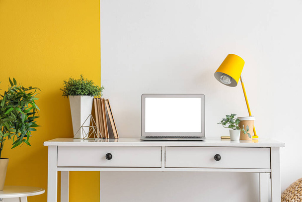 Moderno lugar de trabajo con portátil en blanco y plantas artificiales en la oficina - Foto, Imagen