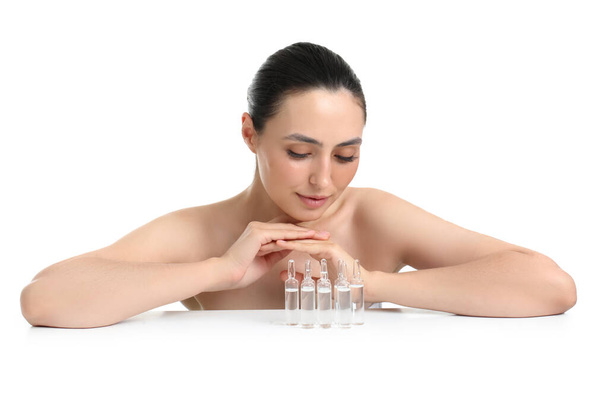 白い背景に対するテーブル上のアンペアを持つ美しい若い女性 - 写真・画像