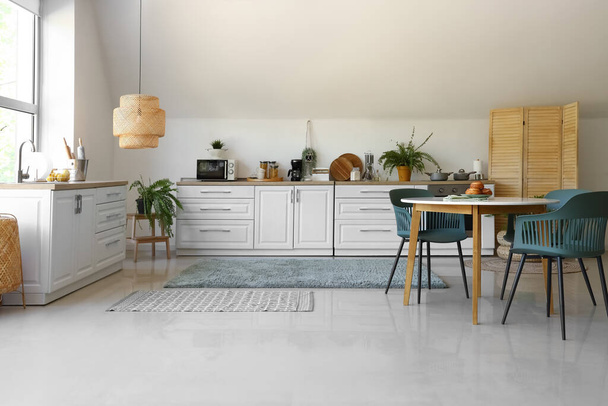 Интерьер современной кухни с белыми столиками и обеденным столом - Фото, изображение