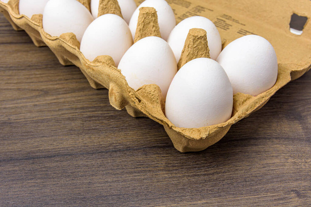 Primer plano de los huevos de granja en una caja de cartón sobre una mesa de nogal oscuro - Foto, imagen