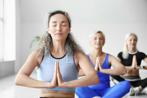 Sportos érett nők meditálnak tornateremben - Fotó, kép