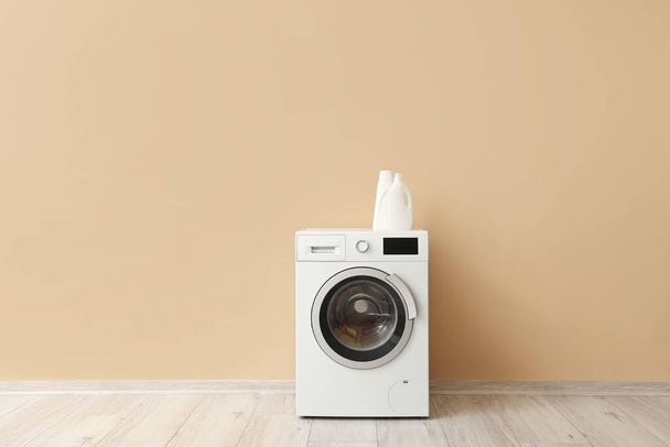 Machine à laver avec détergent à lessive près du mur beige - Photo, image