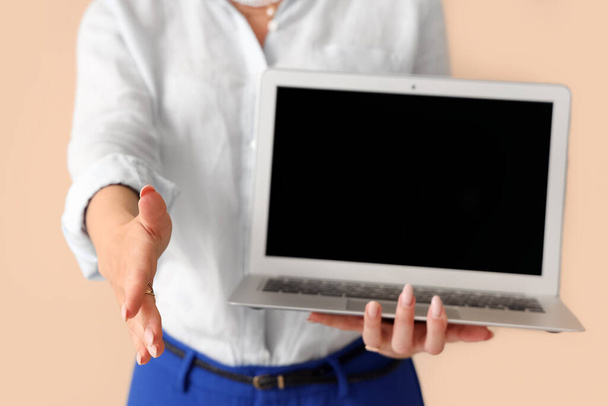 Mooie zakenvrouw met laptop op beige achtergrond, close-up - Foto, afbeelding