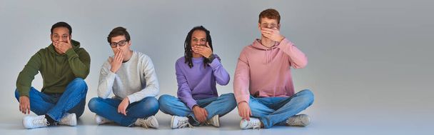 vier junge Freunde sitzen mit gekreuzten Beinen und bedecken den Mund, kulturelle Vielfalt, Banner - Foto, Bild