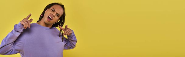 zaskoczony i zszokowany Afrykański Amerykanin w fioletowej bluzie z przekłuwającymi palcami, sztandar - Zdjęcie, obraz