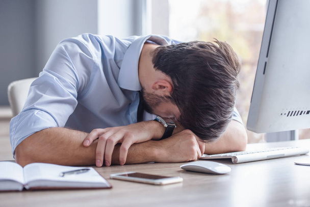 Pohledný podnikatel unavený je opřena o stůl při práci s počítačem v kanceláři - Fotografie, Obrázek