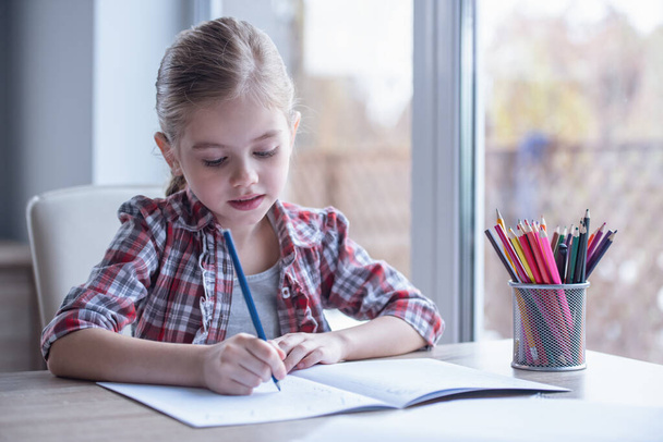 Carina bambina sta disegnando e sorridendo mentre trascorre del tempo a casa
 - Foto, immagini