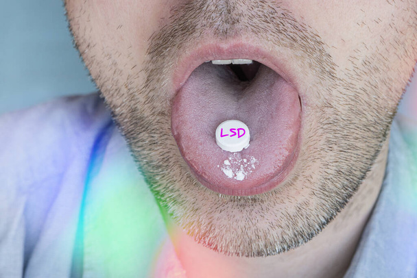 The guy swallows a pill with narcotic acid in close-up. Dependence on synthetic drugs. - Photo, Image