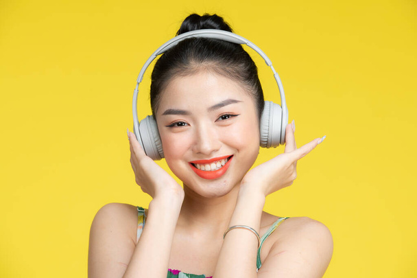 Relaxační, krásná mladá asijská žena se těší hudbu na žlutém pozadí - Fotografie, Obrázek