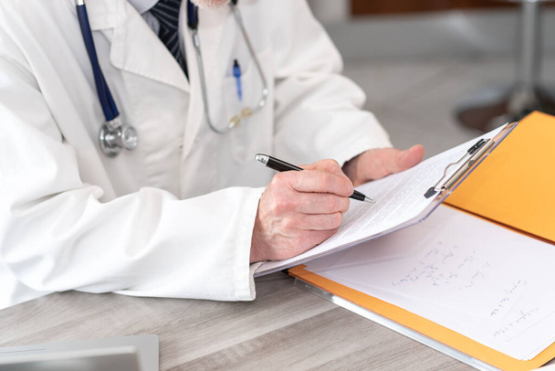 Doctor taking notes on clipboard in medical office - Fotoğraf, Görsel