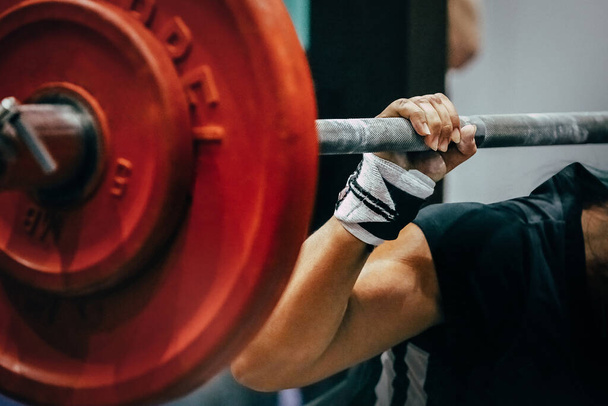 close-up rode platen lange halter en arm vrouwelijke powerlifter tijdens squat - Foto, afbeelding
