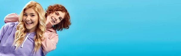 szőke tini lány vörös hajú szórakozás stúdió és nevetés a kamera kék, banner - Fotó, kép
