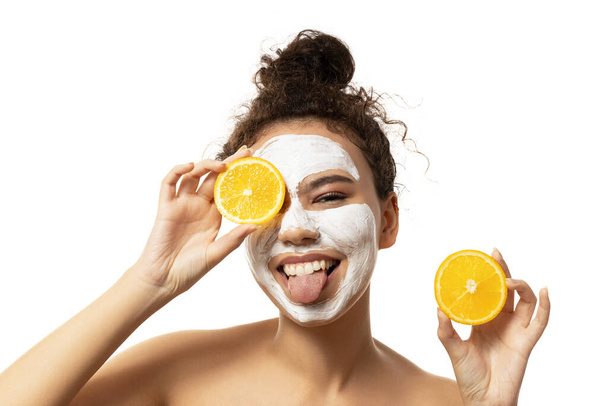PNG, atractiva chica con crema en la cara y naranjas en las manos, aislada sobre fondo blanco - Foto, Imagen