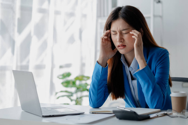 Asian woman in a startup company office, businesswoman poses stressed and body aches due to long hours of hard work, office syndrome among working people. Office syndrome concept and hard work. - Photo, Image