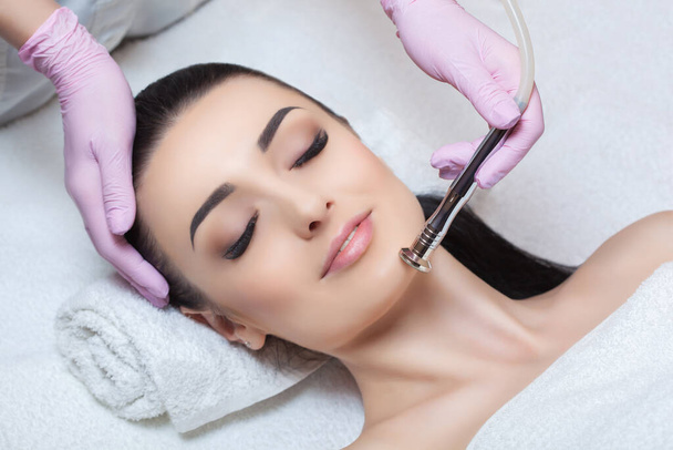 The cosmetologist makes the procedure Microdermabrasion of the facial skin of a beautiful, young woman in a beauty salon.Cosmetology and professional skin care. - Photo, Image