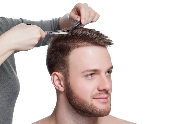 Перукар робить зачіску для молодого чоловіка в перукарні
. - Фото, зображення