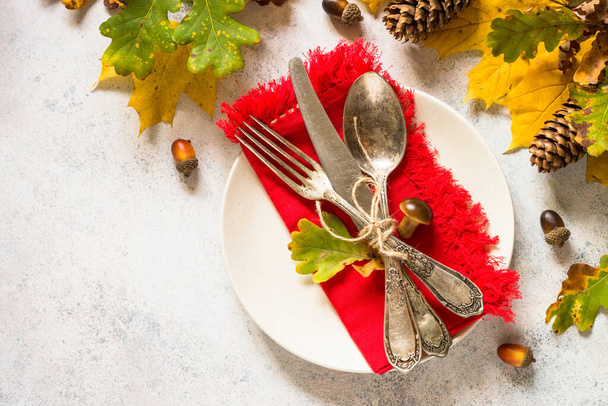 Thanksgiving Food Konzept. Herbstliche Tischdekoration mit weißem Teller, Besteck und Herbstdekoration am weißen Tisch. Draufsicht mit Kopierraum. - Foto, Bild
