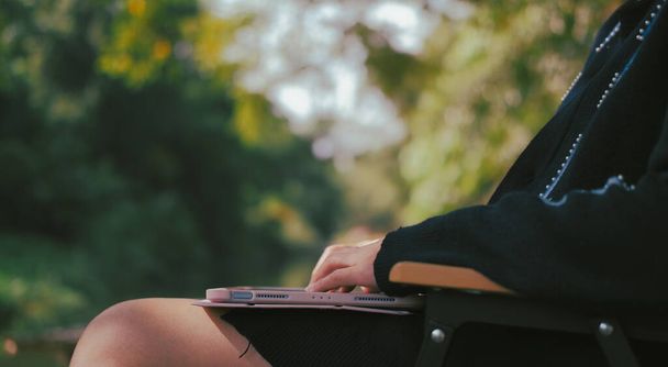 Woman relaxing with laptop in garden Suitable for making infographics. - Photo, Image