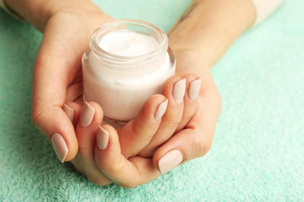 Female hands with jar of cream on fabric background - Foto, imagen