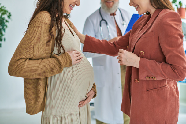 彼女のパートナーと妊娠中のレズビアンの女性の隣に立っている医師の見た目,ivf概念 - 写真・画像