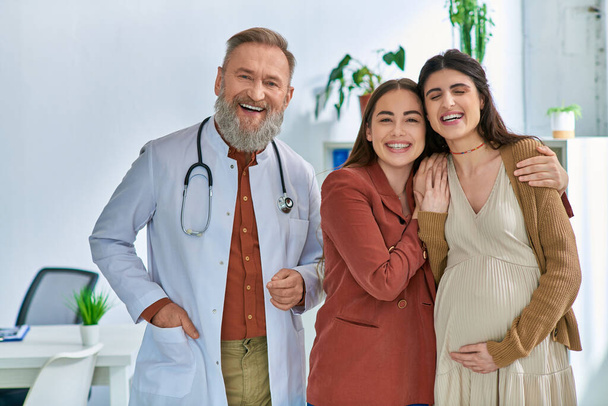 весела пара lgbt, яка очікує, що їх дитина стоїть біля свого сірого бородатого лікаря, концепція IVf - Фото, зображення