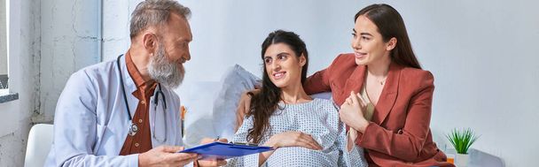 gelukkig lesbisch paar met medische controle op zwangerschap op zoek naar vrolijke dokter, ivf concept, banner - Foto, afbeelding