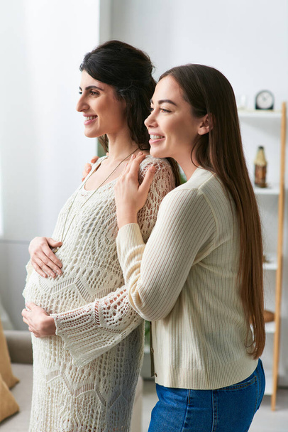 χαμογελαστή προσδοκώντας λεσβιακό ζευγάρι αγκαλιάζει θερμά κοιτάζοντας έξω από το παράθυρο, in vitro έννοια γονιμοποίηση - Φωτογραφία, εικόνα