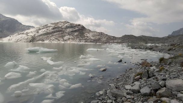 Fellaria smeltende gletsjer laten ijsbergen vallen - stukken ijs drijven we in het meer als gevolg van hoge temperatuur dooi - Opwarming van de aarde en klimaatverandering in Europa, Italië Alpen - Foto, afbeelding