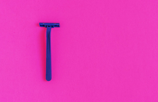 Máquina de afeitar de plástico azul no permanente aislada sobre fondo rosa - Foto, imagen