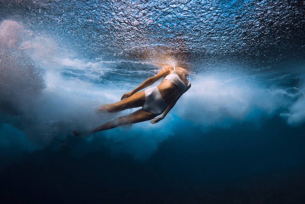 Женщина ныряет под океанские волны. Утка ныряет под разрушающейся бочковой волной в прозрачном океане - Фото, изображение