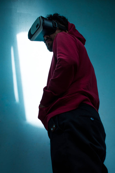 Uomo con giacca rossa e auricolare VR su sfondo blu - Foto, immagini