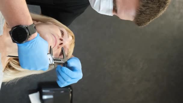 Лікар готує літню жінку до пластичної хірургії на обличчі. Перфорація обличчя перед пластичною хірургією. Концепція пластичної хірургії обличчя. Вертикальне відео - Кадри, відео