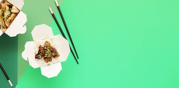 Cajas con sabrosa comida china y palillos sobre fondo verde con espacio para texto - Foto, imagen