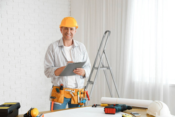 Mature builder with clipboard working in room - Photo, Image