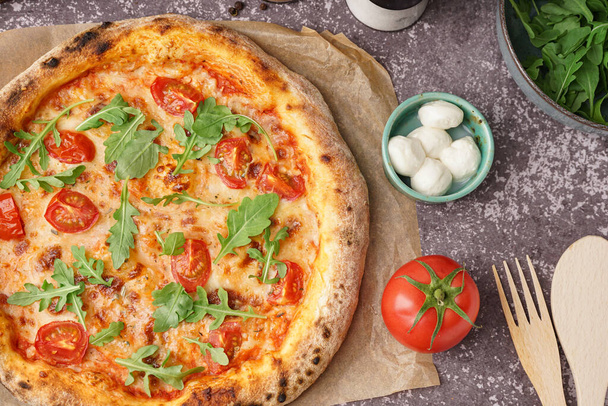 Papel de assar com pizza saborosa Margarita e tigela de mussarela na mesa escura - Foto, Imagem