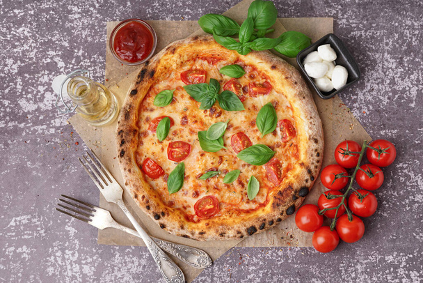 Papel de assar com pizza saborosa Margarita e tigela de mussarela na mesa escura - Foto, Imagem