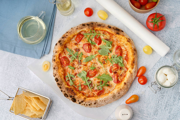 Tasty pizza Margarita with tomatoes and arugula on light blue table - Photo, Image