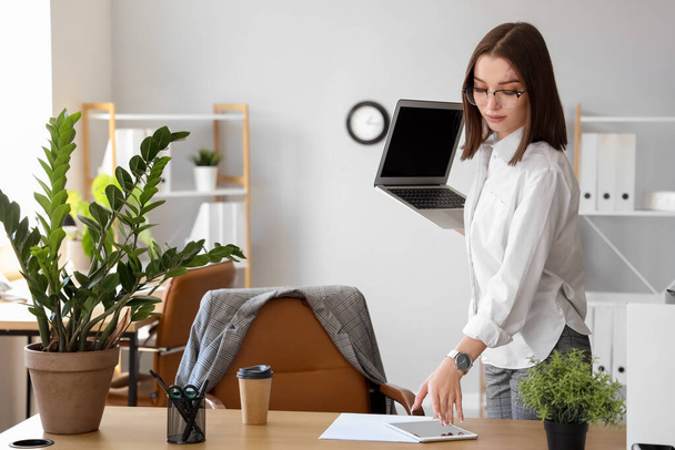 Giovane donna d'affari con computer portatile e tablet che lavora in ufficio - Foto, immagini