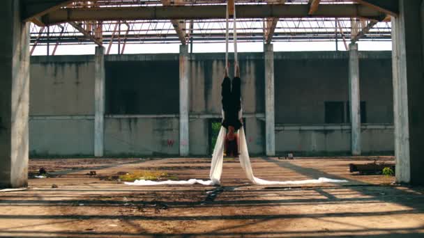 un homme asiatique pend au-dessus du sol tandis que ses pieds sont attachés avec un chiffon blanc dans un vieux bâtiment en fin d'après-midi - Séquence, vidéo